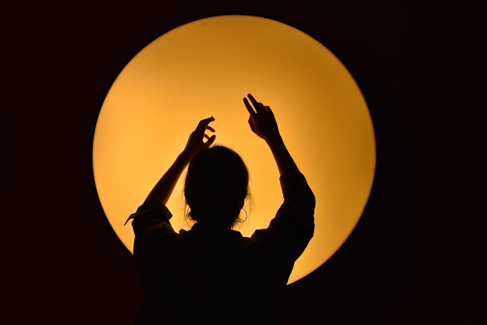 silhouette of woman raising her hands