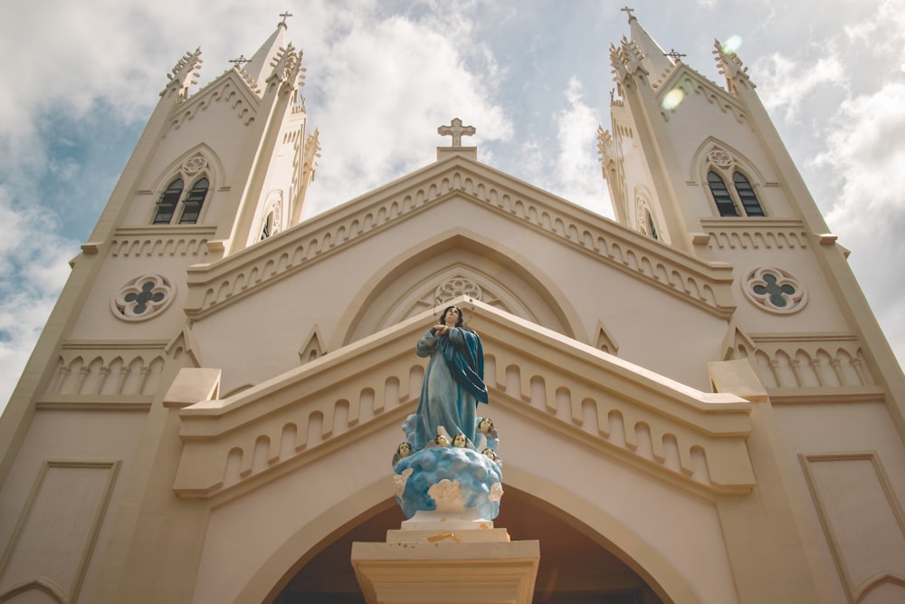 white concrete building with statue under white clouds during daytime