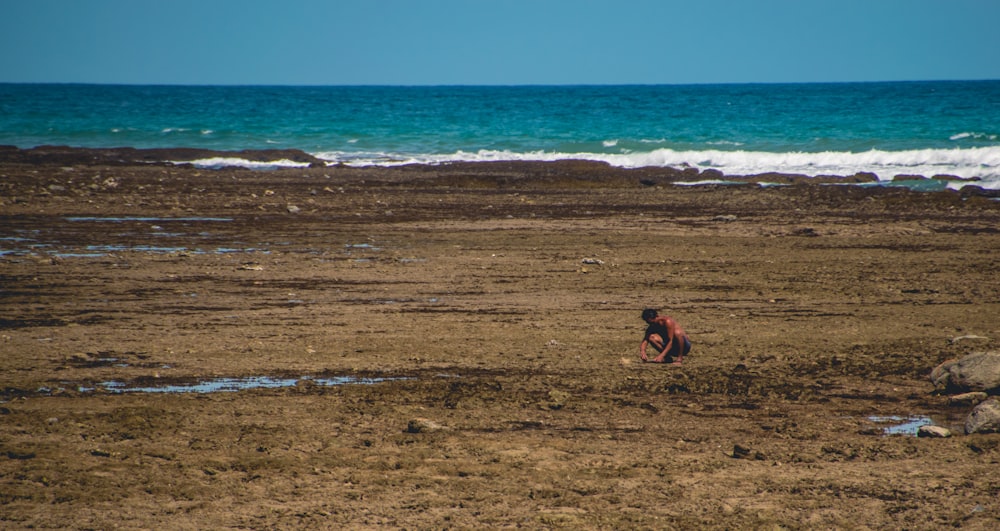 mulher no biquíni preto sentado na praia costa durante o dia