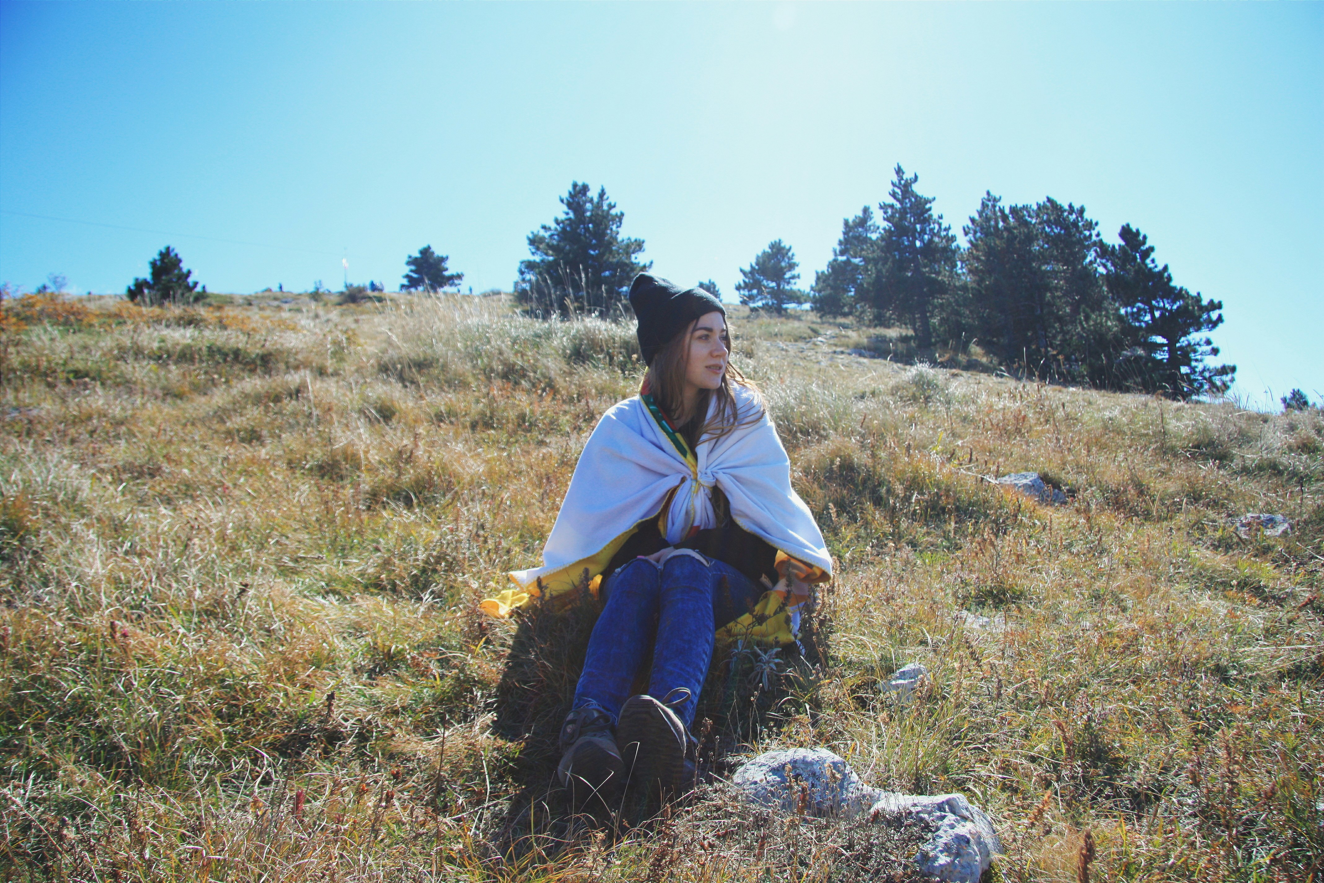 woman in green and yellow dress sitting on brown grass field during daytime