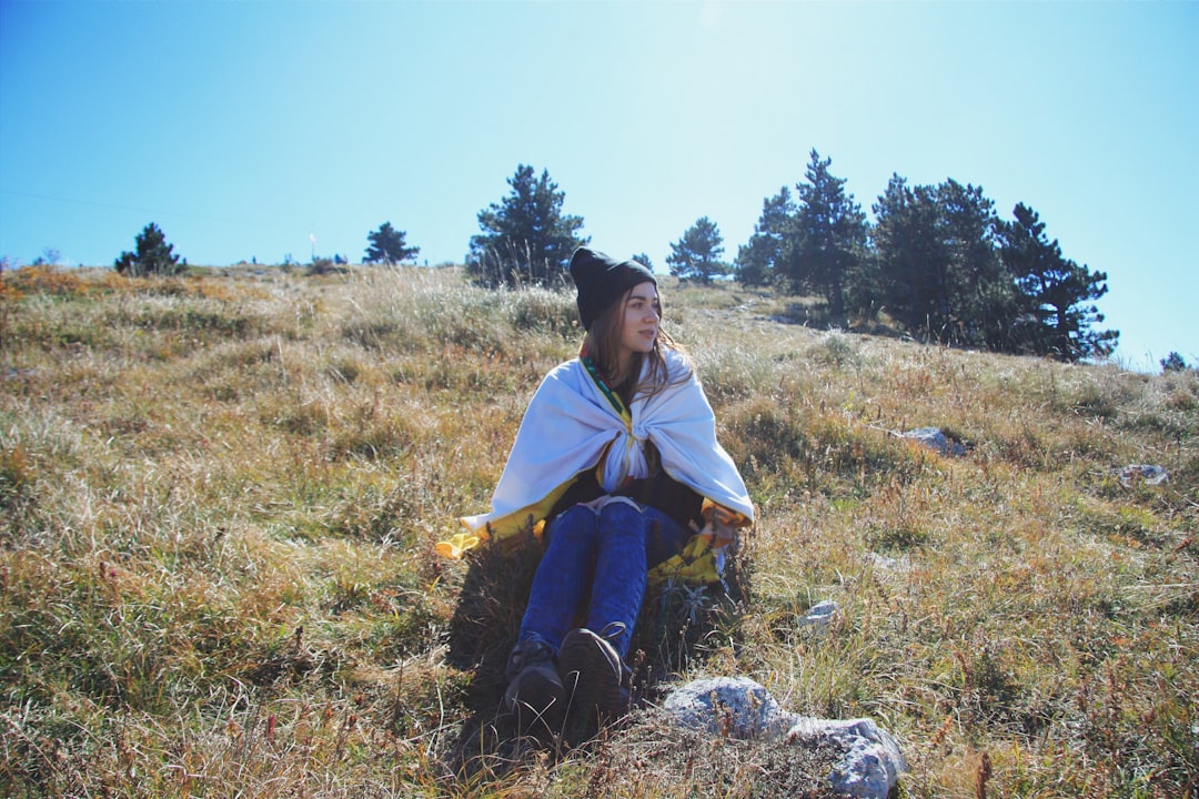 woman in green and yellow dress sitting on brown grass field during daytime