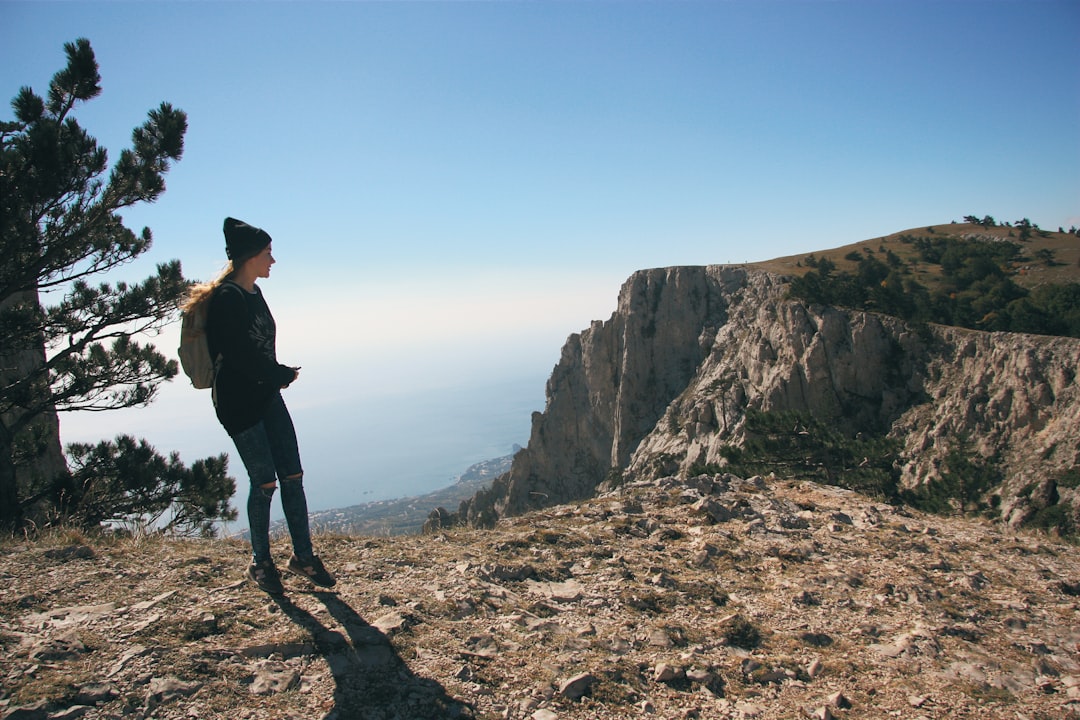 man in black jacket standing on brown rocky mountain during daytime