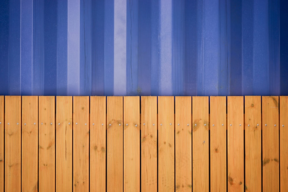 una recinzione di legno con un muro a strisce blu dietro di esso