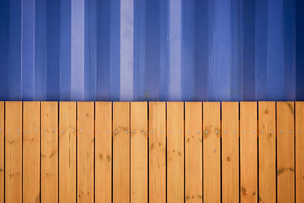 una valla de madera con una pared de rayas azules detrás de ella