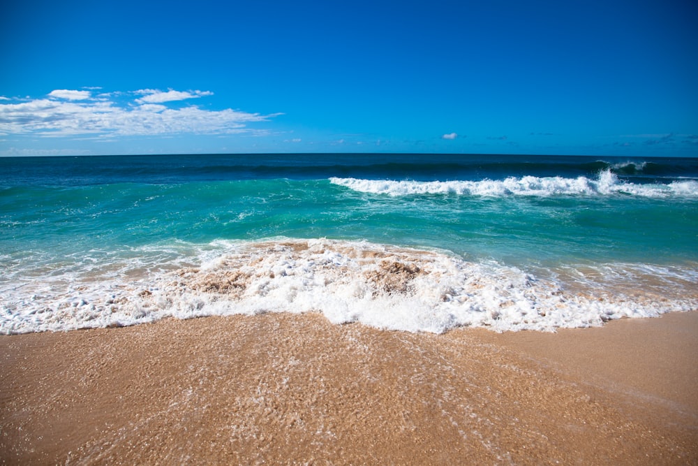 a sandy beach with waves coming in and out of the water