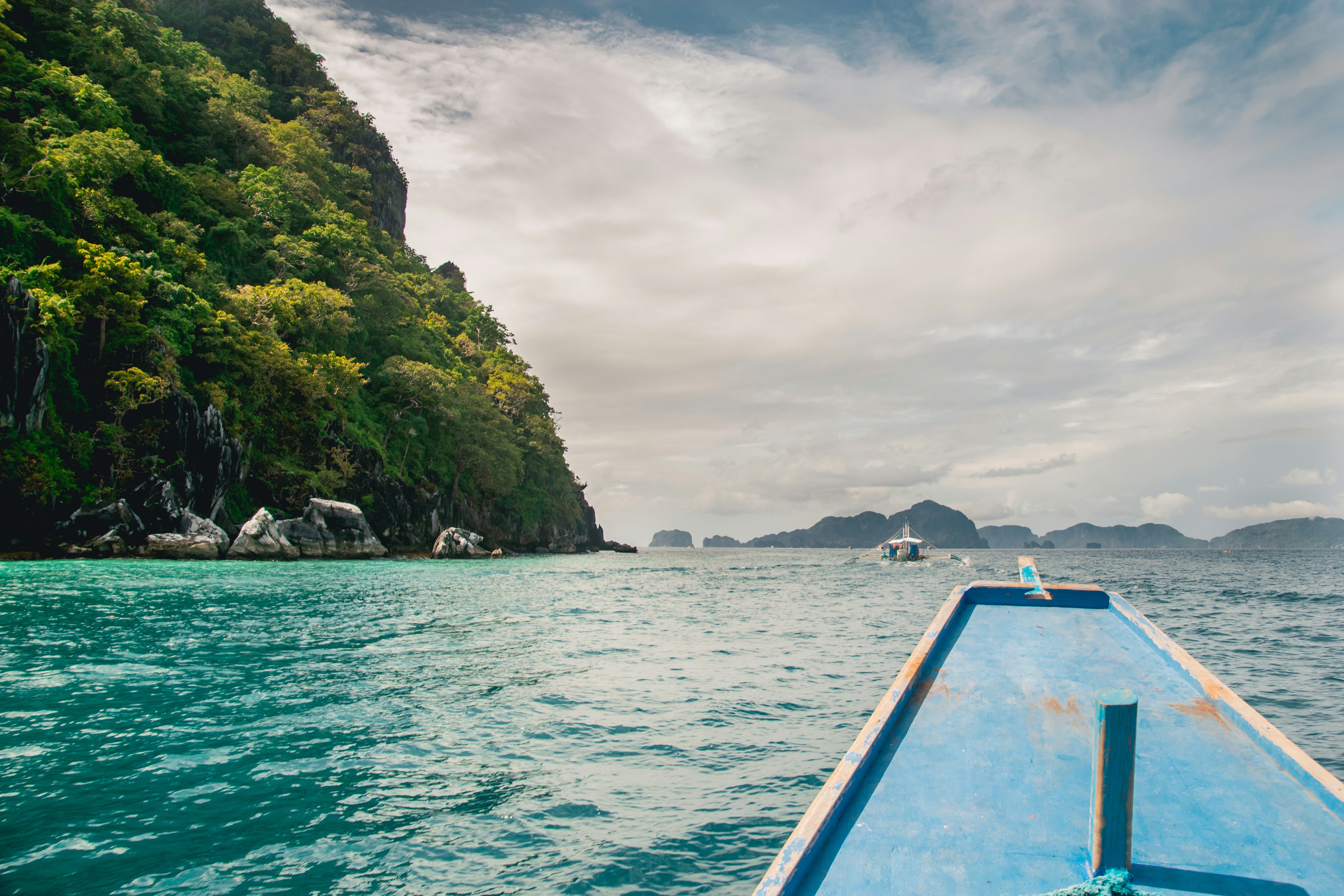 Blau-weißes Boot auf See in der Nähe von Green und Brown Island unter weißen Wolken während des Tages