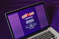 A laptop displays a screen with a vibrant purple background featuring the text 'Wash & Vax' with stylized virus iconography above it. Detailed text below outlines a call to action related to vaccines and social distancing, with a prominent 'start' button visible.