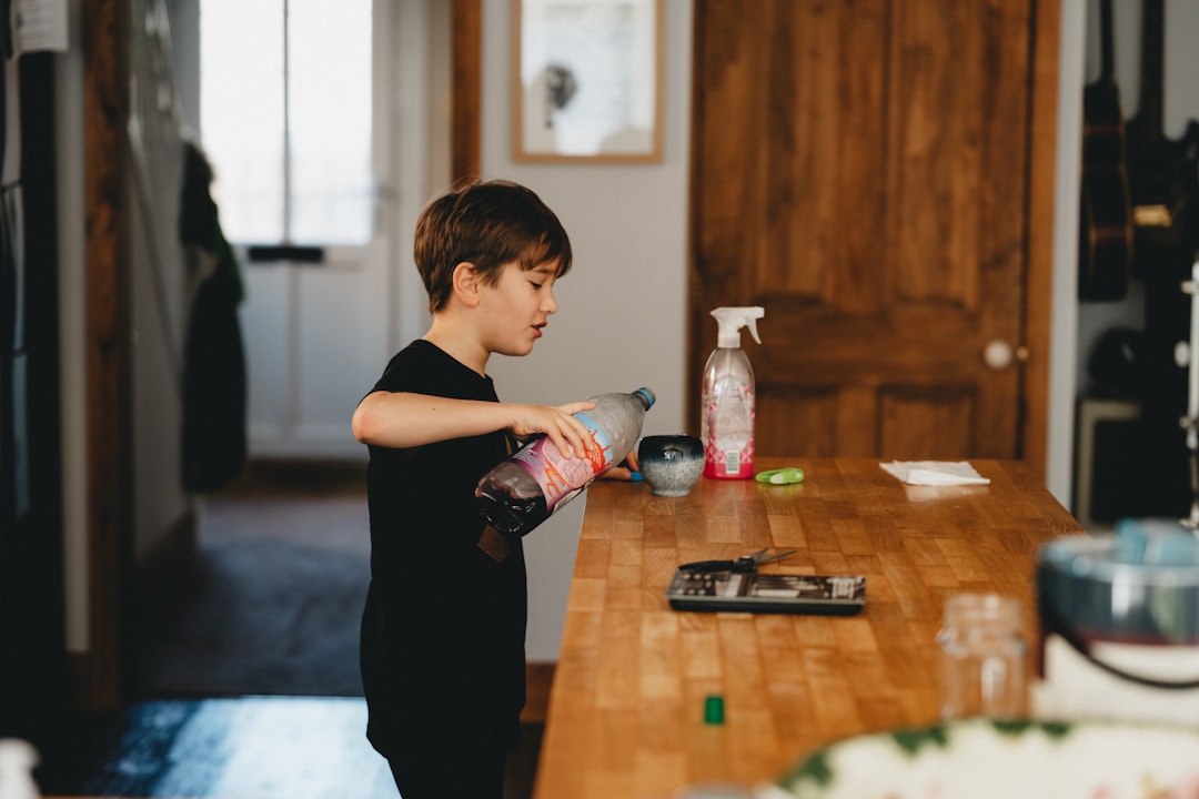 boy in black t-shirt holding clear plastic bottle