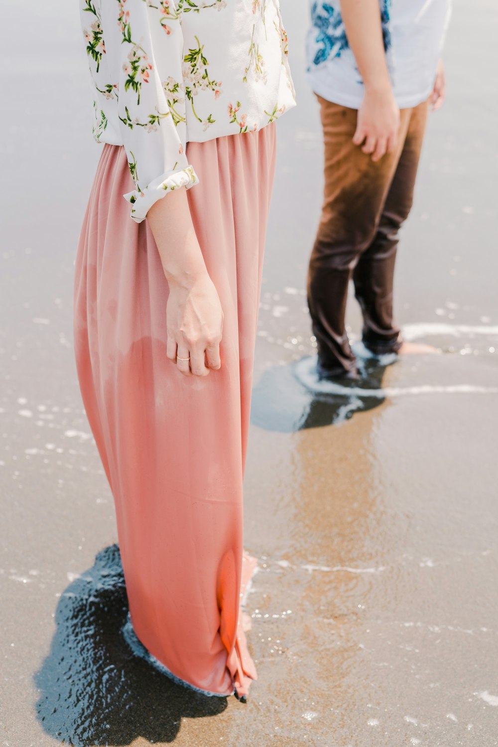 a man and woman standing on a beach next to the ocean