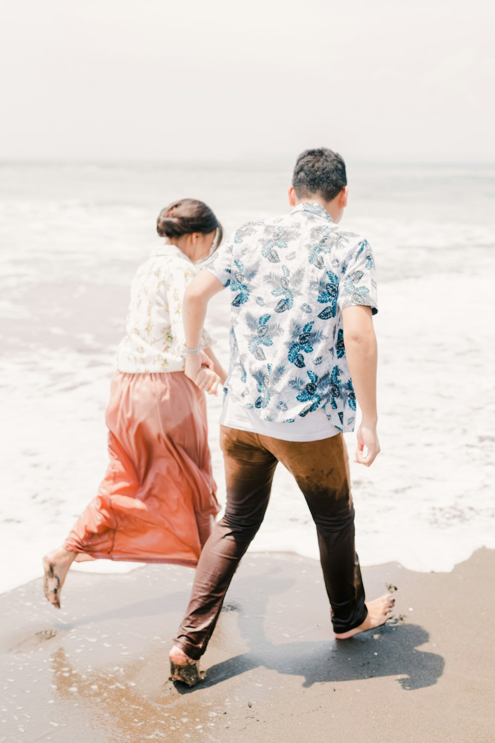 um homem e uma mulher que caminham na praia