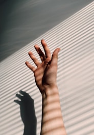 persons left hand on white window blinds