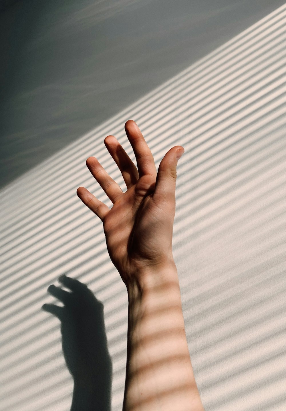 persons left hand on white window blinds