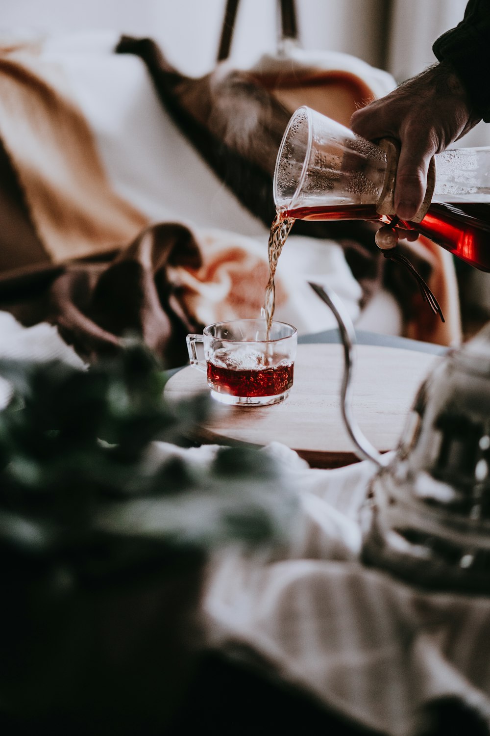 personne versant un liquide rouge sur un verre à boire transparent