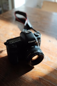 A sleek professional camera resting on a wooden table with soft natural light.
