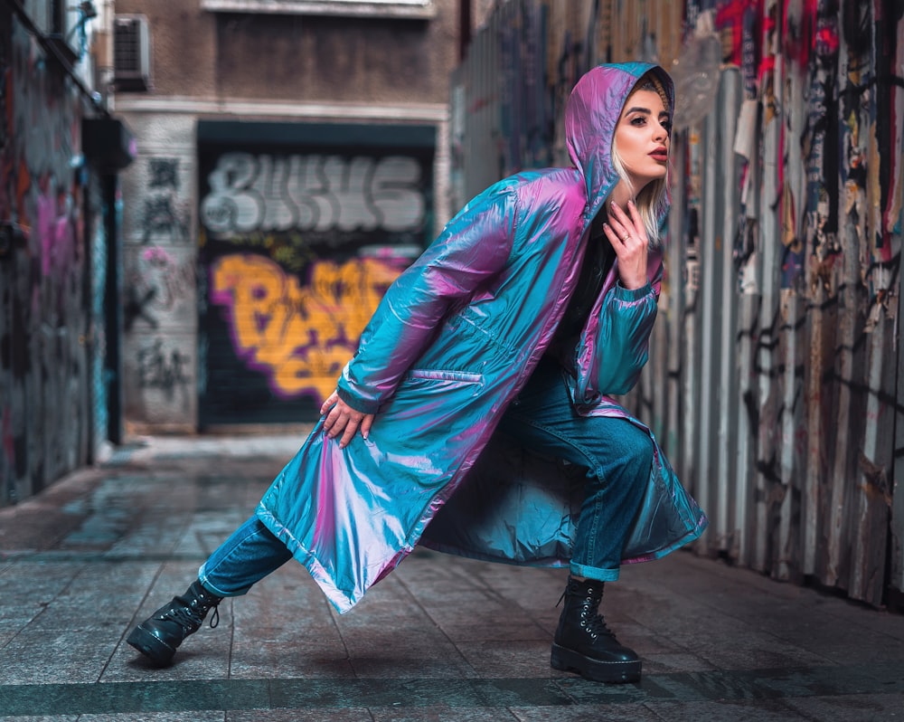 woman in purple leather jacket and black pants sitting on sidewalk during daytime