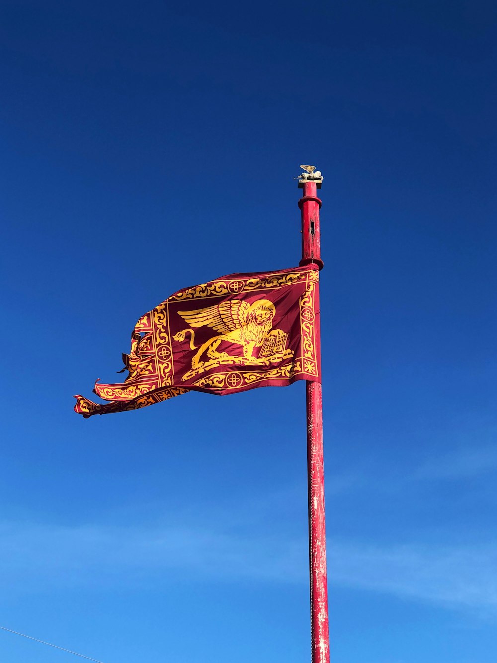 bandeira vermelha e dourada sob o céu azul durante o dia