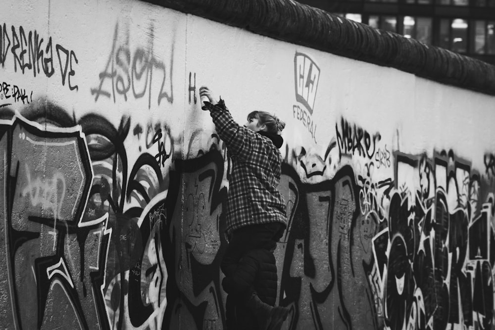 man in black and white stripe long sleeve shirt and black pants sitting on concrete wall