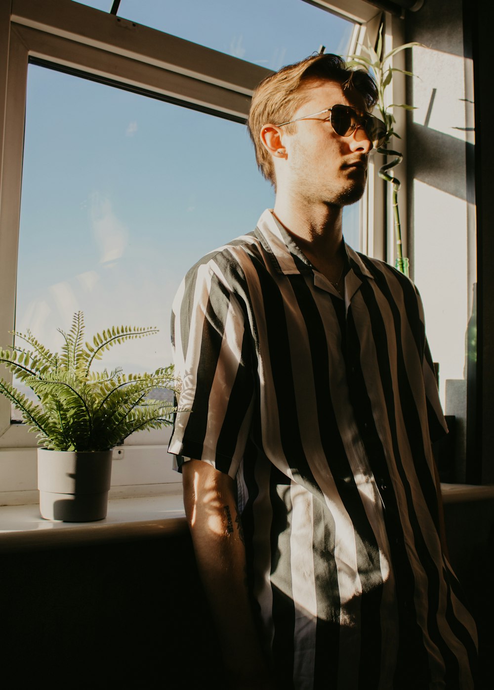 Homme en polo à rayures noires et blanches portant des lunettes de soleil noires