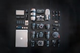 silver macbook black dslr camera and black dslr camera