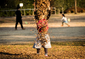 A joyful child in colorful, trendy clothes playing in a sunlit park with autumn leaves