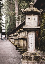 Pilgrims walking along a peaceful path lined with ancient stone lanterns and blooming marigolds.