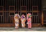 2 women in kimono standing on sidewalk during daytime