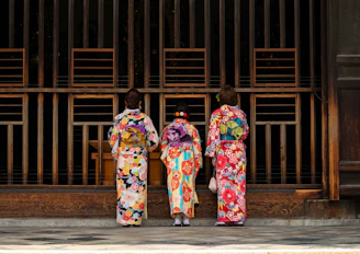2 women in kimono standing on sidewalk during daytime