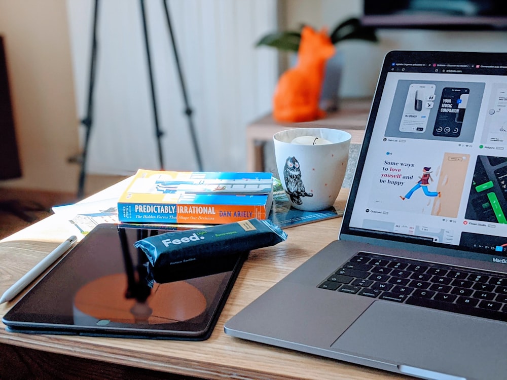 macbook pro beside white ceramic mug on brown wooden table