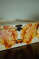 Close-up of a box lid featuring delicate floral patterns hand-painted in pink and gold.
