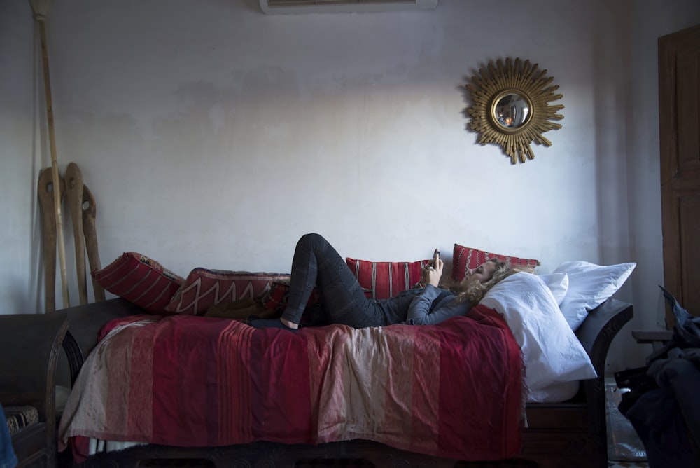 person in blue denim jeans lying on red couch