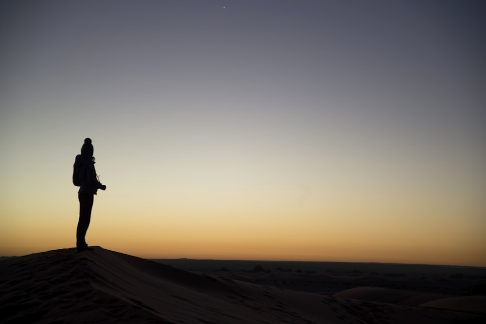 silhouette of person on desert during sunset