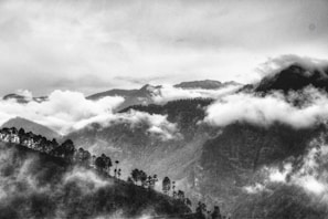 Black and white photo of a misty mountain range at dawn, evoking quiet reflection.