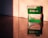 Two boxes of Fujifilm camera film sit on a reflective surface, with warm, soft lighting casting shadows and highlights. The top box is labeled 'FUJIFILM Superia X-TRA 400', and the bottom one is marked 'FUJICOLOR C200'. The labels are clearly visible, and the reflection enhances the warm tones.