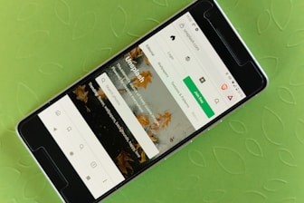 A smartphone displaying a website interface with a prominent green button labeled 'Join free.' The screen shows a search bar and various categories like Editorial, Wallpapers, and Textures & Patterns. The background is a textured, light green surface with a leaf pattern.