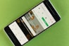 A smartphone displaying a website interface with a prominent green button labeled 'Join free.' The screen shows a search bar and various categories like Editorial, Wallpapers, and Textures & Patterns. The background is a textured, light green surface with a leaf pattern.