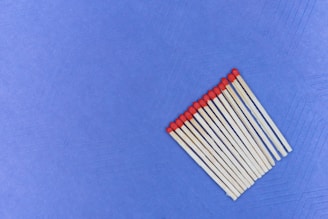 A group of wooden matchsticks with red tips arranged in parallel on a textured blue surface.