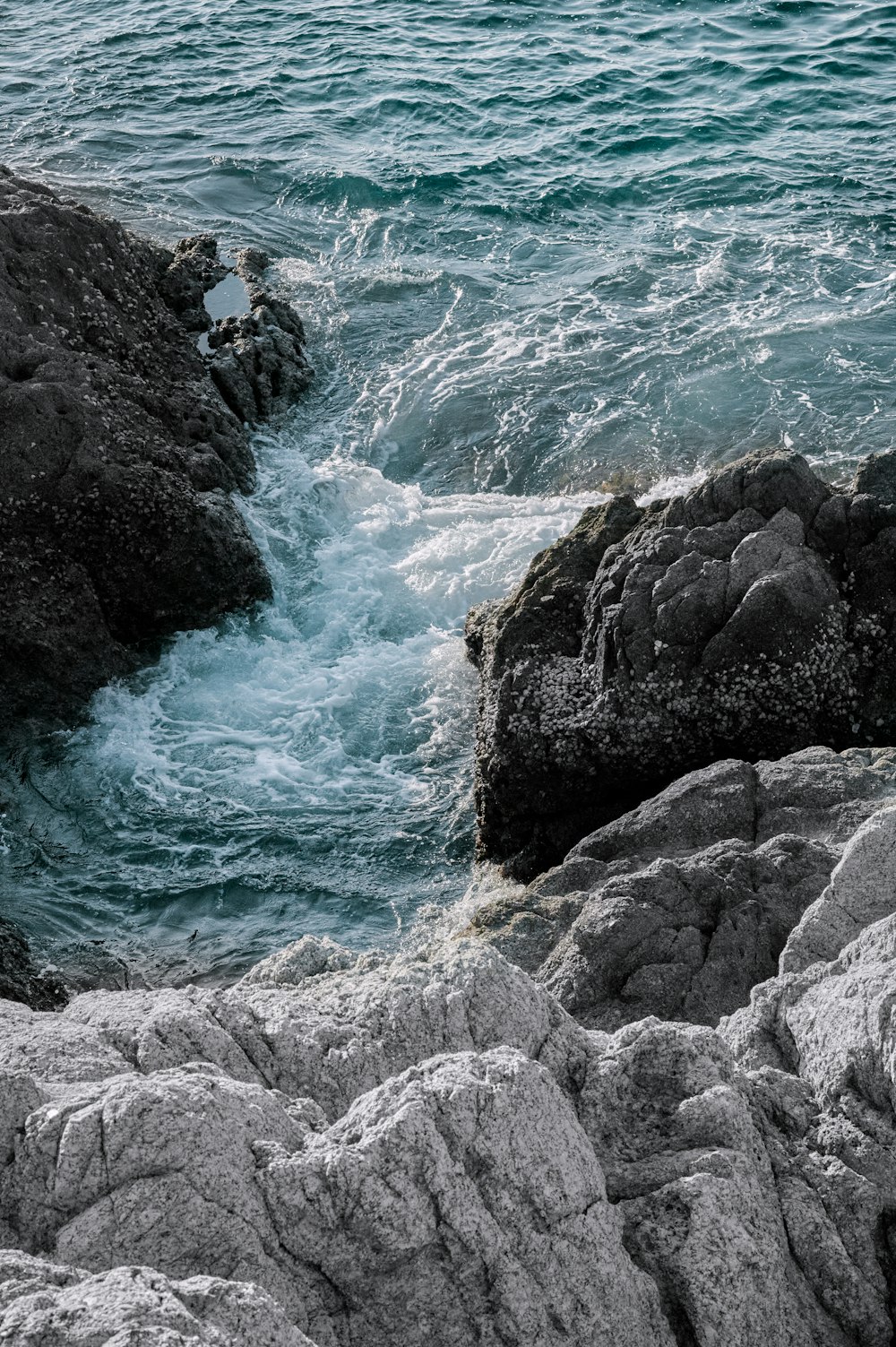 black rock formation on body of water during daytime