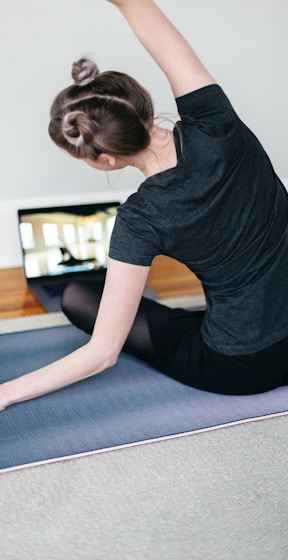 woman in black t-shirt and black pants lying on black yoga mat