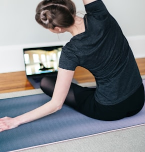 woman in black t-shirt and black pants lying on black yoga mat