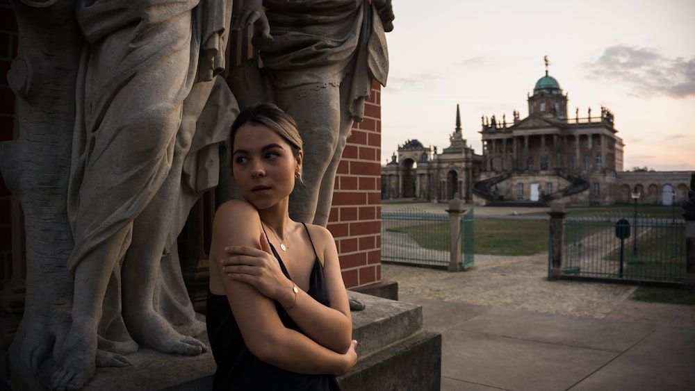 woman in black tank top sitting on gray concrete bench during daytime