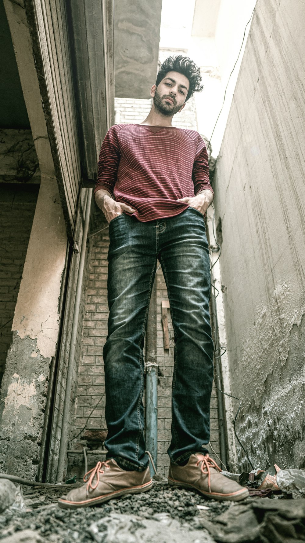 man in red and white striped shirt and blue denim jeans standing on stairs