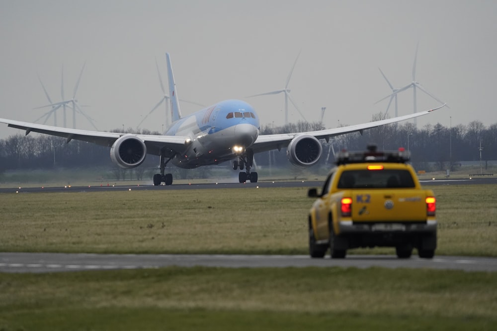 voiture jaune sur la route près de l’avion blanc pendant la journée