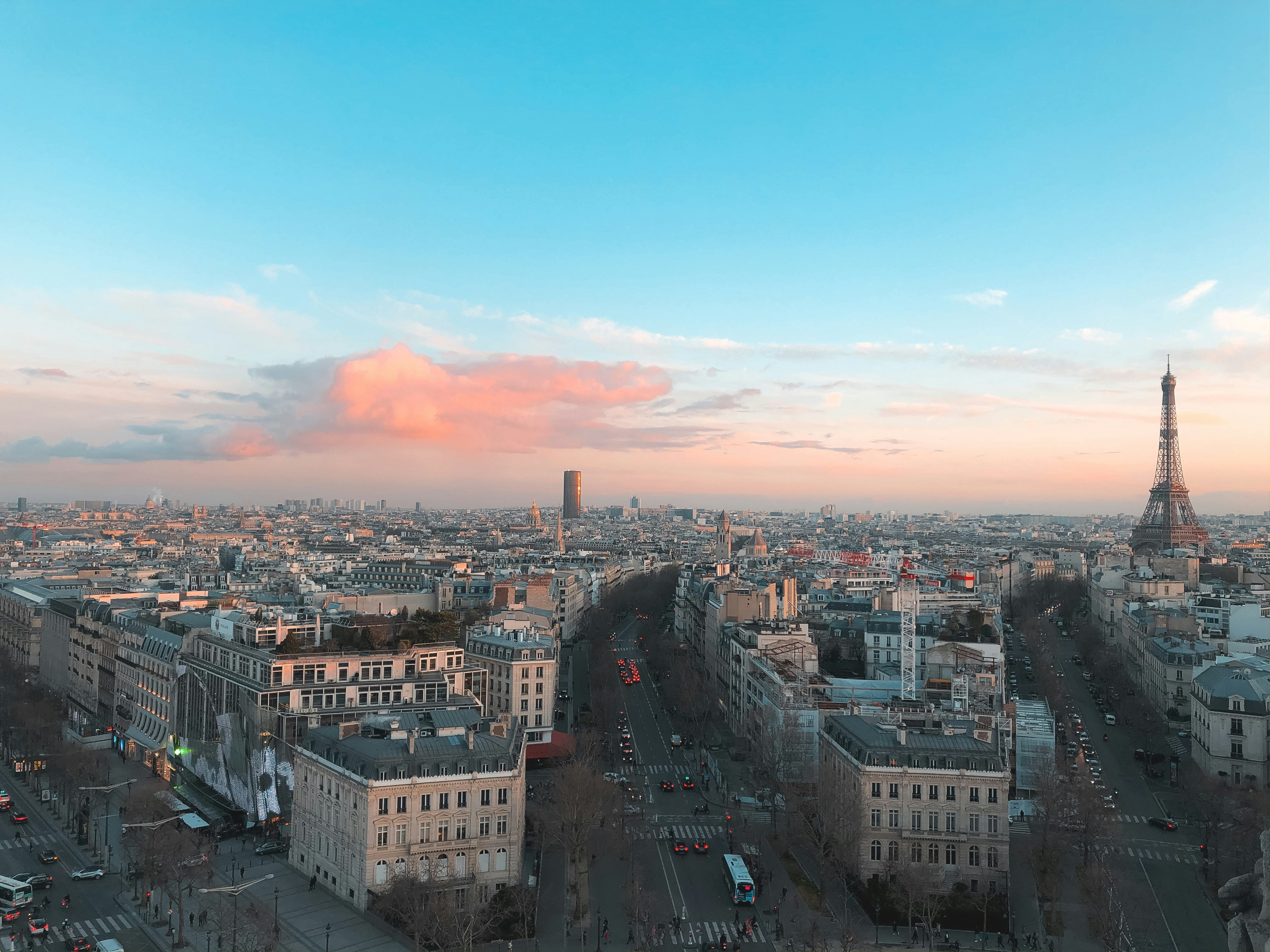 Torre Eiffel illuminata al tramonto con cielo rosa e Parigi sfocata sullo sfondo