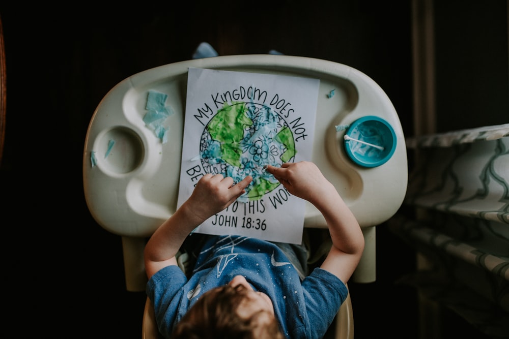 girl in blue t-shirt sitting on white toilet bowl