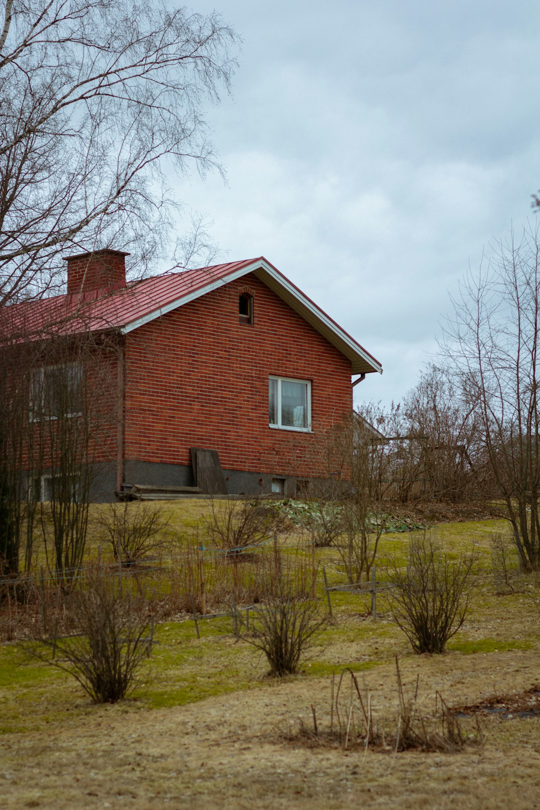 brown brick house near bare trees under cloudy sky during daytime