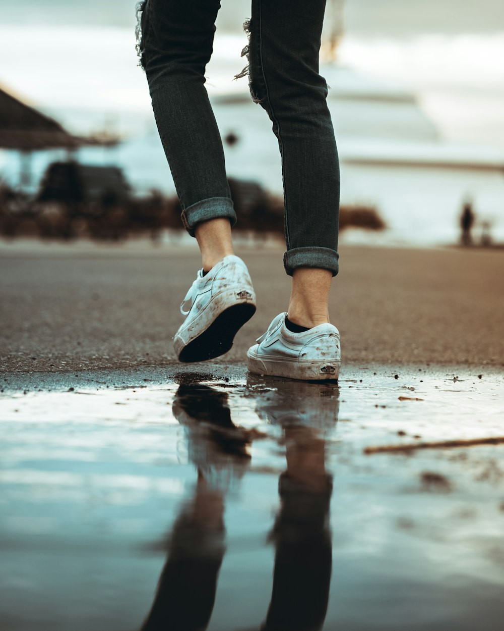 person in blue denim jeans and white and black nike sneakers standing on wet ground