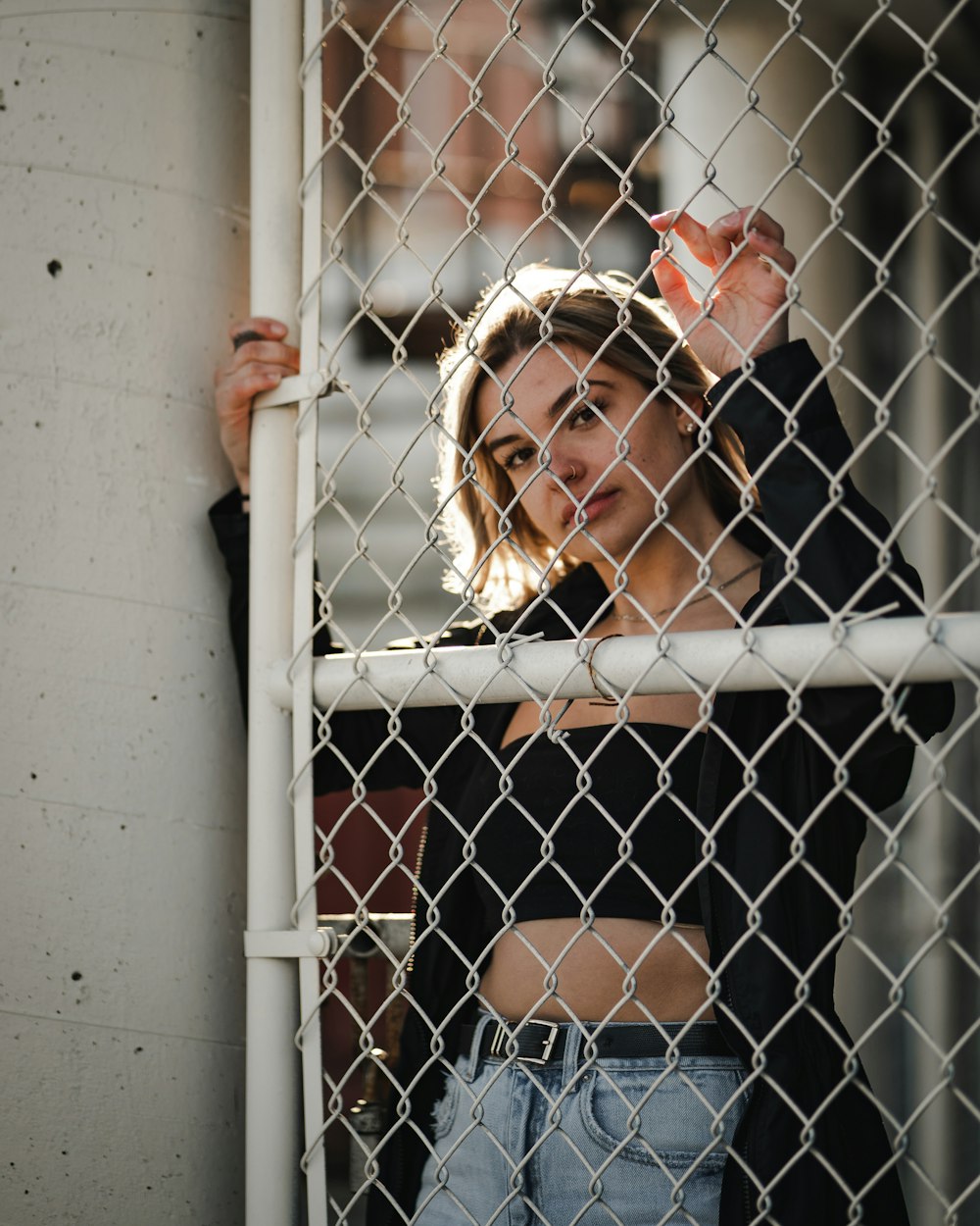 woman in black off shoulder shirt leaning on white metal fence