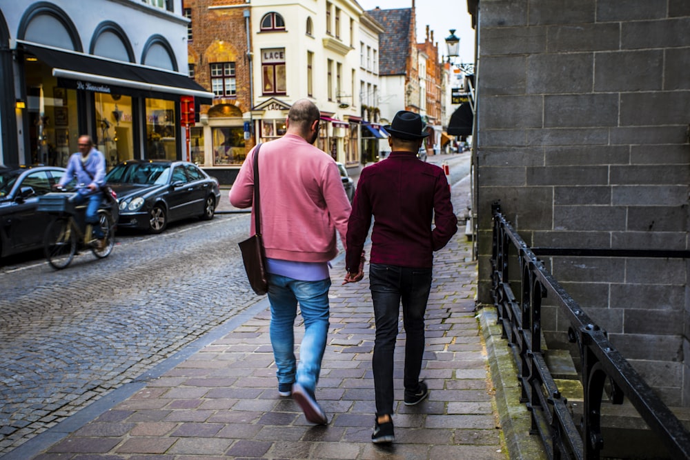 man in red hoodie and blue denim jeans walking on sidewalk during daytime