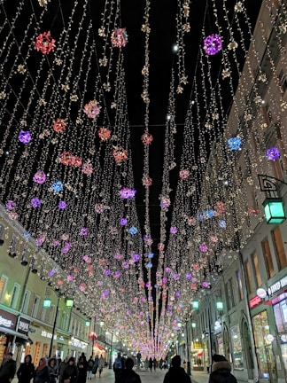 Street lit up with colorful Christmas lights and festive decorations.