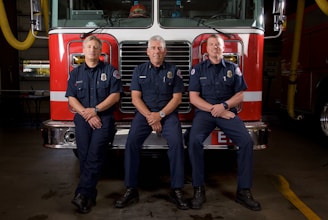 Volunteer firefighters in black and safety green uniforms standing proudly in front of the East Campbell Fire Department station.